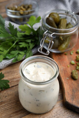 Tasty tartar sauce in glass jar on wooden table