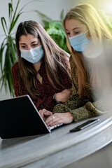 Female friends are browsing on their laptop at home or are chatting with their friends  on a social...