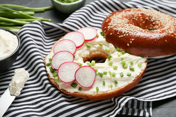 Delicious bagel with cream cheese, green onion and radish on table, closeup - obrazy, fototapety, plakaty