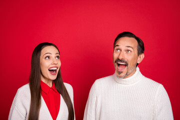 Photo of amazed curious cheerful mature man and woman look empty space sale news isolated on red color background