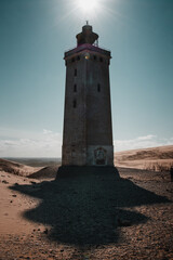 Exploring the famous ancient Rubjerg knude fyr place in the endless sand dunes. Desert like sand dunes with the landmark lighthouse on a bright summer vacation day. North Jutland, Denmark, Europe - obrazy, fototapety, plakaty