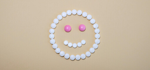 smiley face laid from white pink pills on beige background. Good women's health