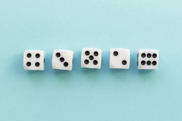 Gaming dice on blue background. Playing cube with numbers. Items for board games. Flat lay, top view with copy space.