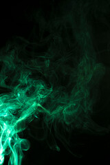 The movement of green smoke takes place on a fierce black background, fearing an abstraction on a black background.