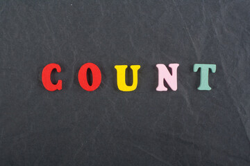 COUNT word on black board background composed from colorful abc alphabet block wooden letters, copy space for ad text. Learning english concept.