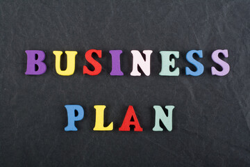 BUSINESS PLAN word on black board background composed from colorful abc alphabet block wooden letters, copy space for ad text. Learning english concept.