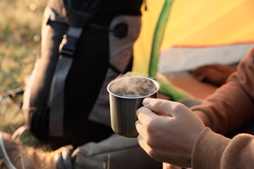 Fototapeta na wymiar Man with cup of hot drink in camping tent, closeup