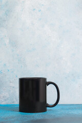 Isolated black coffee mug in a blue background