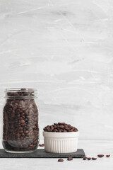 Fototapeta na wymiar A small bowl of coffee beans with a glass jar