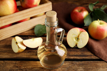 Natural apple vinegar and fresh fruits on wooden table