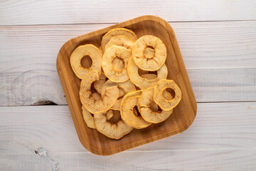 Several crispy apple chips with bamboo crockery on a wooden table, close-up, top view.