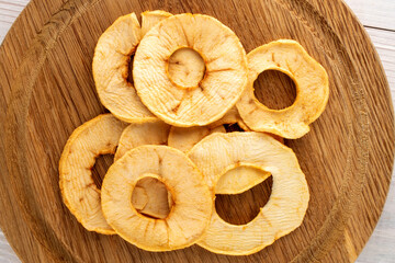 Several crispy apple chips with bamboo crockery on a wooden table, close-up, top view.