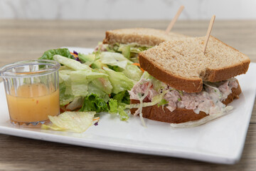 Loaded tuna sandwich on wheat bread with a side of salad for a delicious lunch meal
