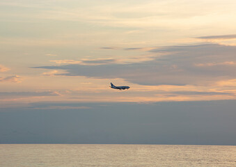 the silhouette of an airplane against the background of the sea and the setting sun.