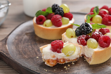 Delicious tartlets with berries on wooden table, closeup