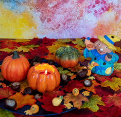 Colorful and autumn Halloween decoration with leaves, pumpkins, a candle and a scarecrow.