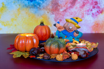 Colorful and autumn Halloween decoration with leaves, pumpkins, candles and a scarecrow.