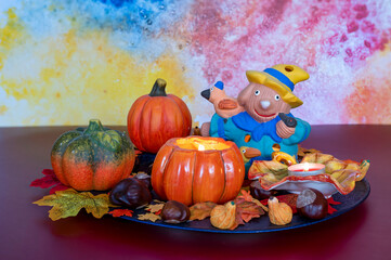 Colorful and autumn Halloween decoration with leaves, pumpkins, candles and a scarecrow.
