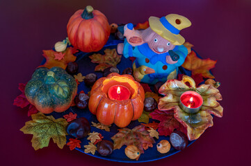 Colorful and autumn Halloween decoration with leaves, pumpkins, candles and a scarecrow.