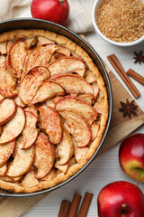 Delicious apple pie and ingredients on white wooden table, flat lay