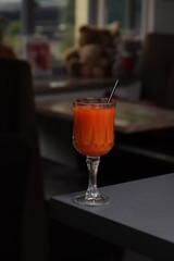 Glass of red-orange smoothie on a gray bar counter
