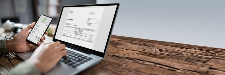 Businessman's Hands Working On Invoice On Laptop