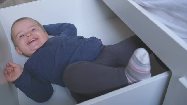 Caucasian Female Revealing Happy Adorable Cute Caucasian Baby Toddler Girl Hiding in Bed Drawer for Pillows and Sheets