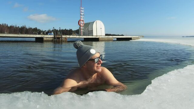 A man swiming in an ice hole in winter. Winter swimming is a traditional sport and recreation in Finland.