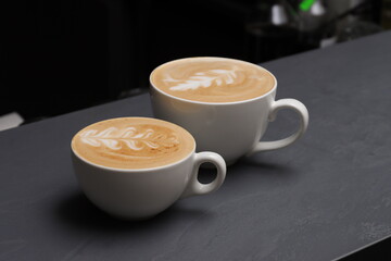 two cups of cappuccino on a gray bar counter