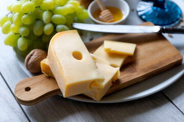 Cheese platter with different cheeses, grapes, nuts, honey. Appetizers table with antipasti snacks. Cheese variety board over white marble background. Top view, flat lay