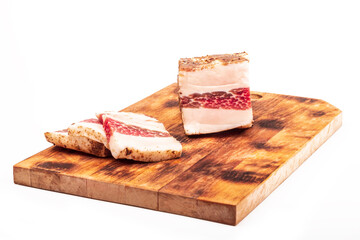 wooden board in retro style. a piece of bacon is cut into pieces on it. on a white background. close-up.