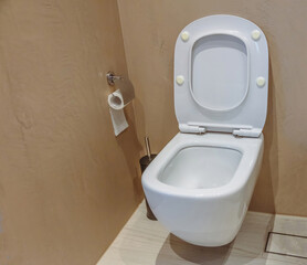 Modern toilet interior design, hanging toilet bowl and brush, beige brown walls and floor.