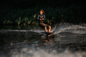 energetic man in wetsuit skillfully balancing on water surface on wakeboard