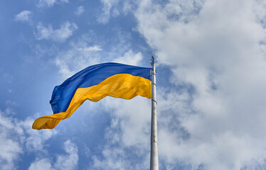 Ukrainian blue and yellow flag. Background of blue sky and white clouds. The national flag of Ukraine. 