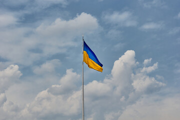 Ukrainian blue and yellow flag. Background of blue sky and white clouds. The national flag of Ukraine. 