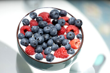 Raspberries and blueberries in a cup with yogurt.