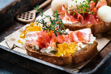 Bruschetta with prosciutto and pesto sauce on plate. Bruschetta with hamon, melon and honey. Spanish appetizer. Italian antipasti. Christmas food.