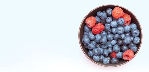 Blueberries mixed with raspberries in a cup, top view.