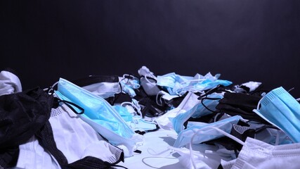 Medical masks on the table. Pile of used personal protective equipment PPE. Pollution by surgical masks during the coronavirus pandemic. A lot of Covid-19 plastic waste and garbage, disposable masks.