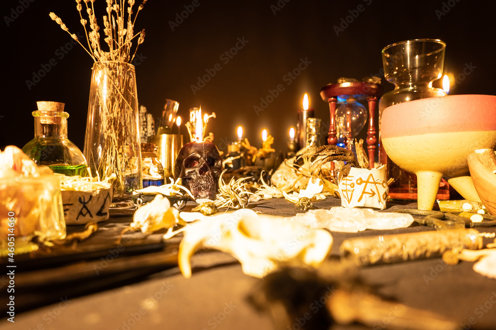 Wall mural Witchcraft still life with burning candles selective focus on skull. Esoteric gothic and occult witch table for Halloween. Magic objects and ritual arrangement. Shallow depth of field.