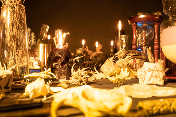 Witchcraft still life with burning candles selective focus on skull. Esoteric gothic and occult witch table for Halloween. Magic objects and ritual arrangement. Shallow depth of field.