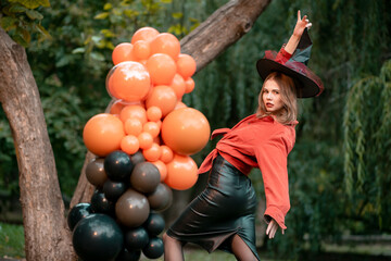 Halloween witch in a black hat. Beautiful young woman dancing in the forest. Halloween party design