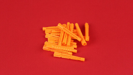 Orange plastic dowels on red background