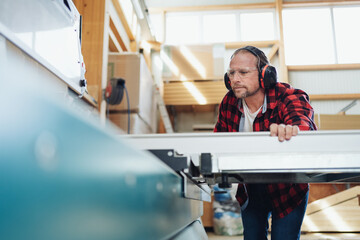 Obraz premium Carpenter or joiner in a factory working with machinery