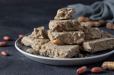 Sweet sunflower halva with peanut on gray plate on dark background. Close-up