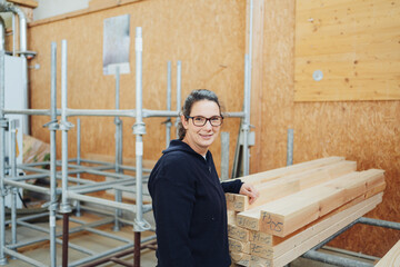 Smiling female worker standing alongside supplies in warehouse
