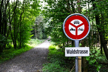 Red no driving sign near a forest road with German sign "Waldstrasse".