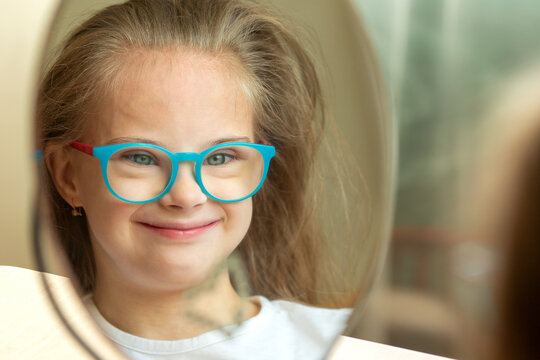 A beautiful girl with Down syndrome combs in front of a mirror