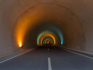 Entrance to empty tunnel road with colorful lighting.