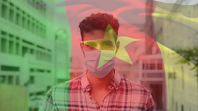 Animation Of Flag Of Cameroon Waving Over Man Wearing Face Mask During Covid 19 Pandemic